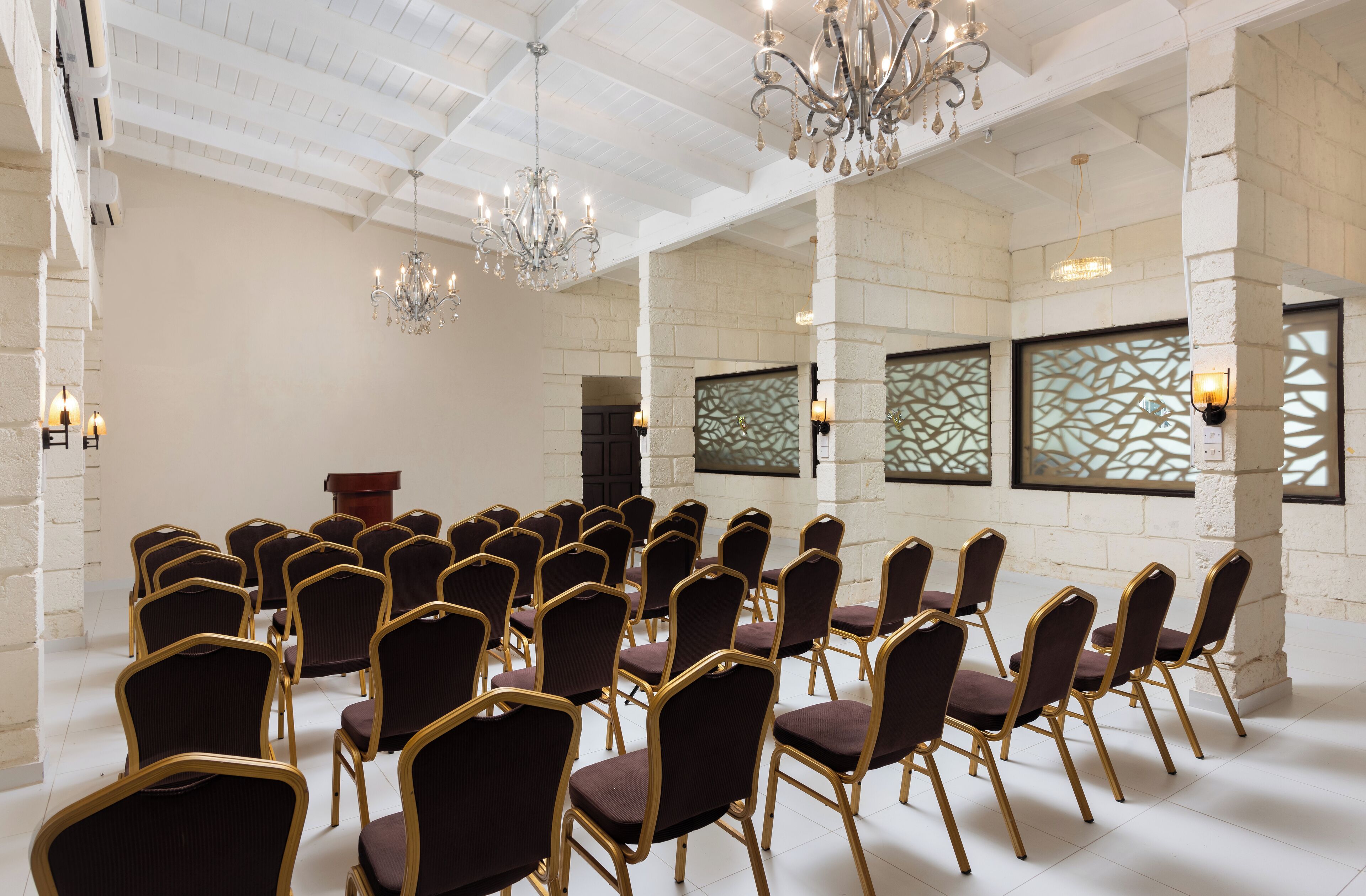 A conference room with rows of chairs, a podium, and chandeliers.