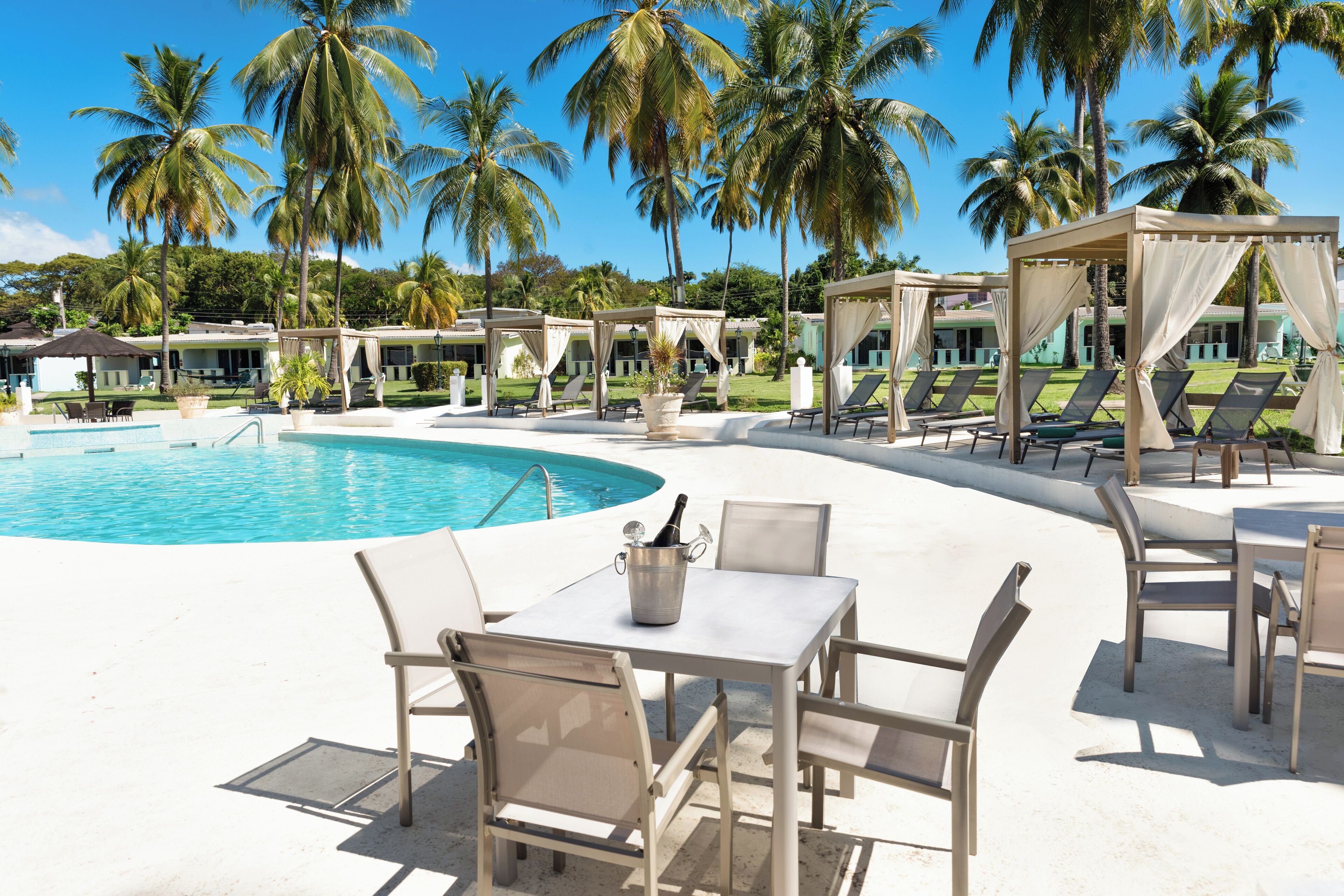 A poolside area with lounge chairs, a table with a bottle, and a gazebo.
