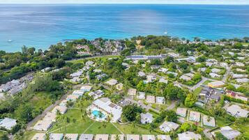Vista aérea de una zona residencial costera con casas, una piscina y vista al océano.