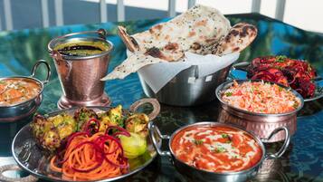 Un tavolo con diversi piatti indiani, tra cui una pentola di rame, una ciotola di curry e pane naan.