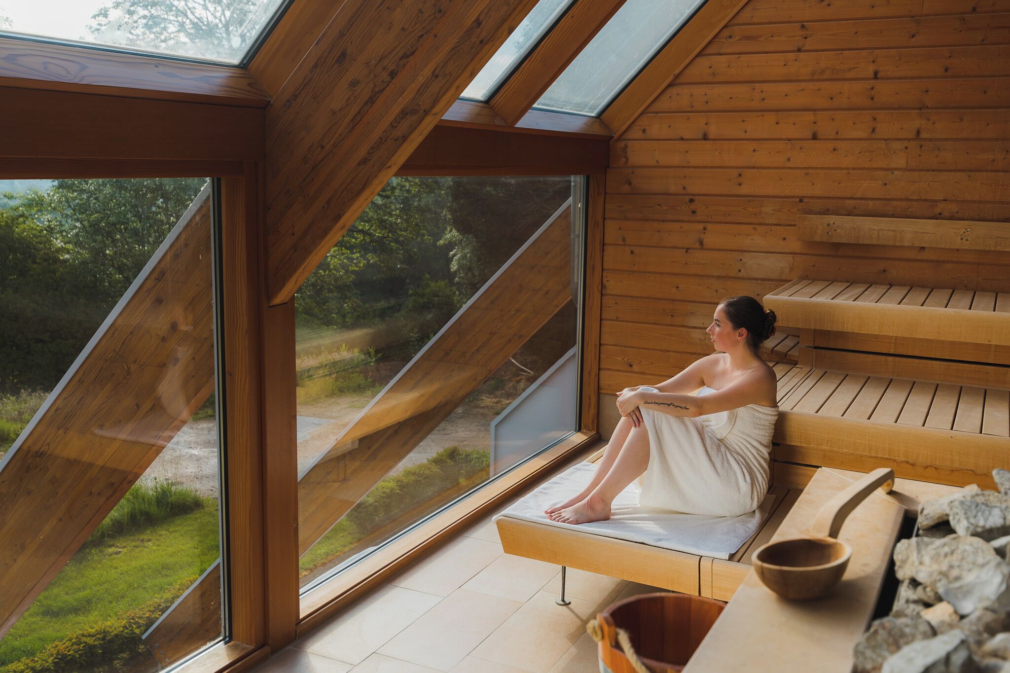 A wooden cabin with a large skylight, a bench, and a sauna area.