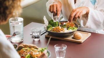 A dining table with a meal, a bottle of water, and a glass.