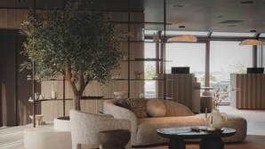 Uma sala de estar moderna com uma grande árvore, um sofá, uma mesa de centro e uma estante de livros.