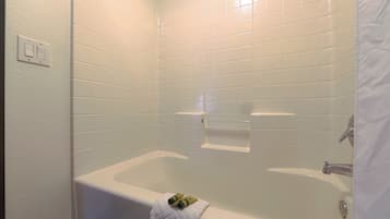 A bathroom with white tiled walls, a bathtub, and a towel rack with a towel.