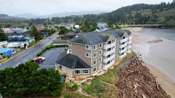 A multi-story building with a parking lot and a beach in the background.