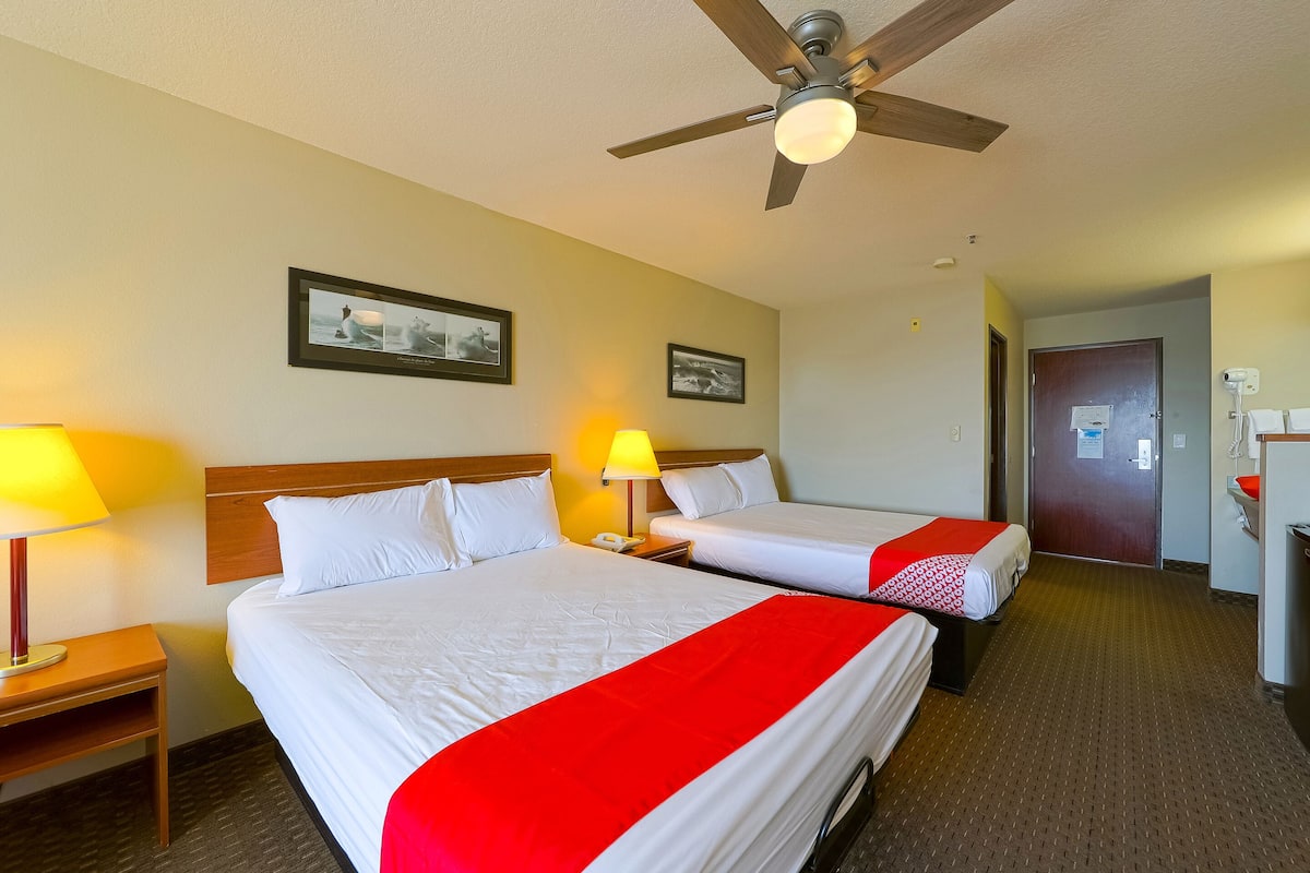 A hotel room with two beds, a ceiling fan, and two bedside lamps.