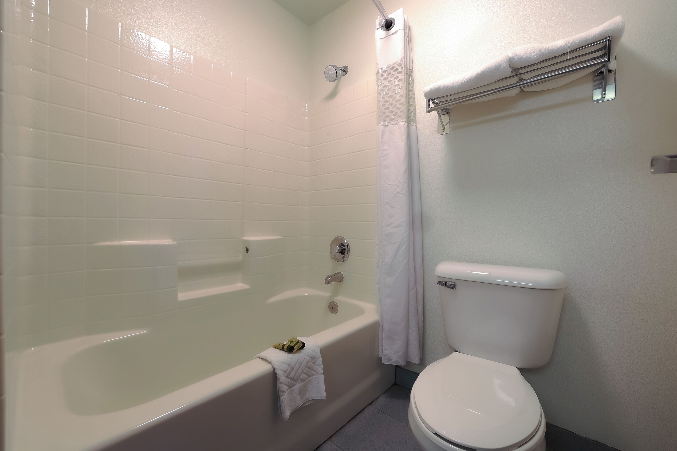 Un baño con bañera, inodoro y toallero.
