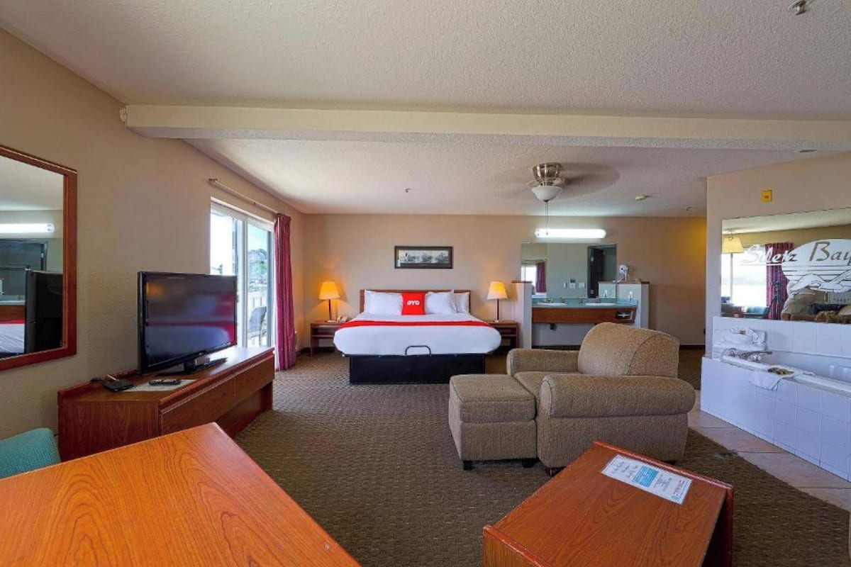 A hotel room with a bed, a TV, a desk, a chair, and a bathroom area.