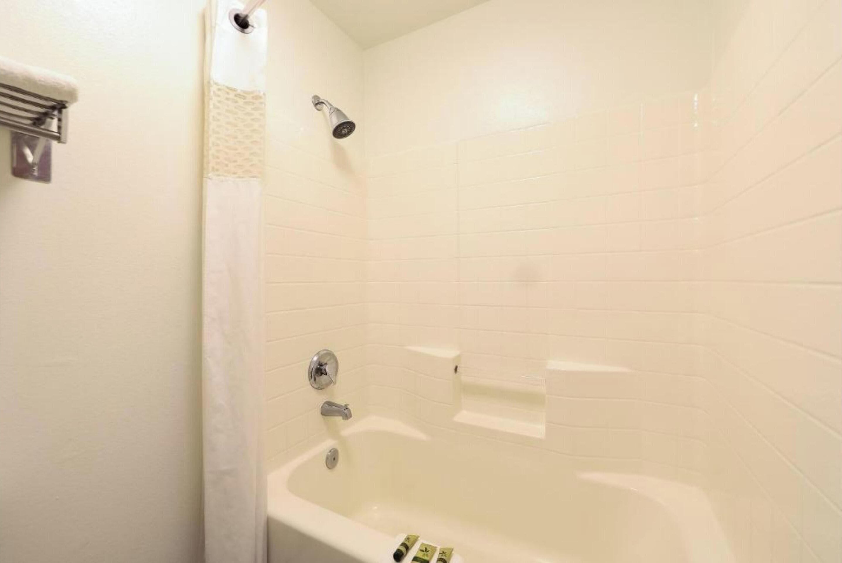 A bathroom with a bathtub, a showerhead, and a towel rack.