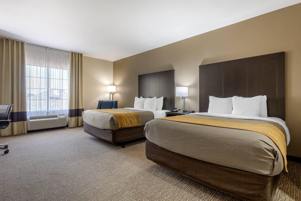 Een hotelkamer met twee bedden, een bureau en een stoel.