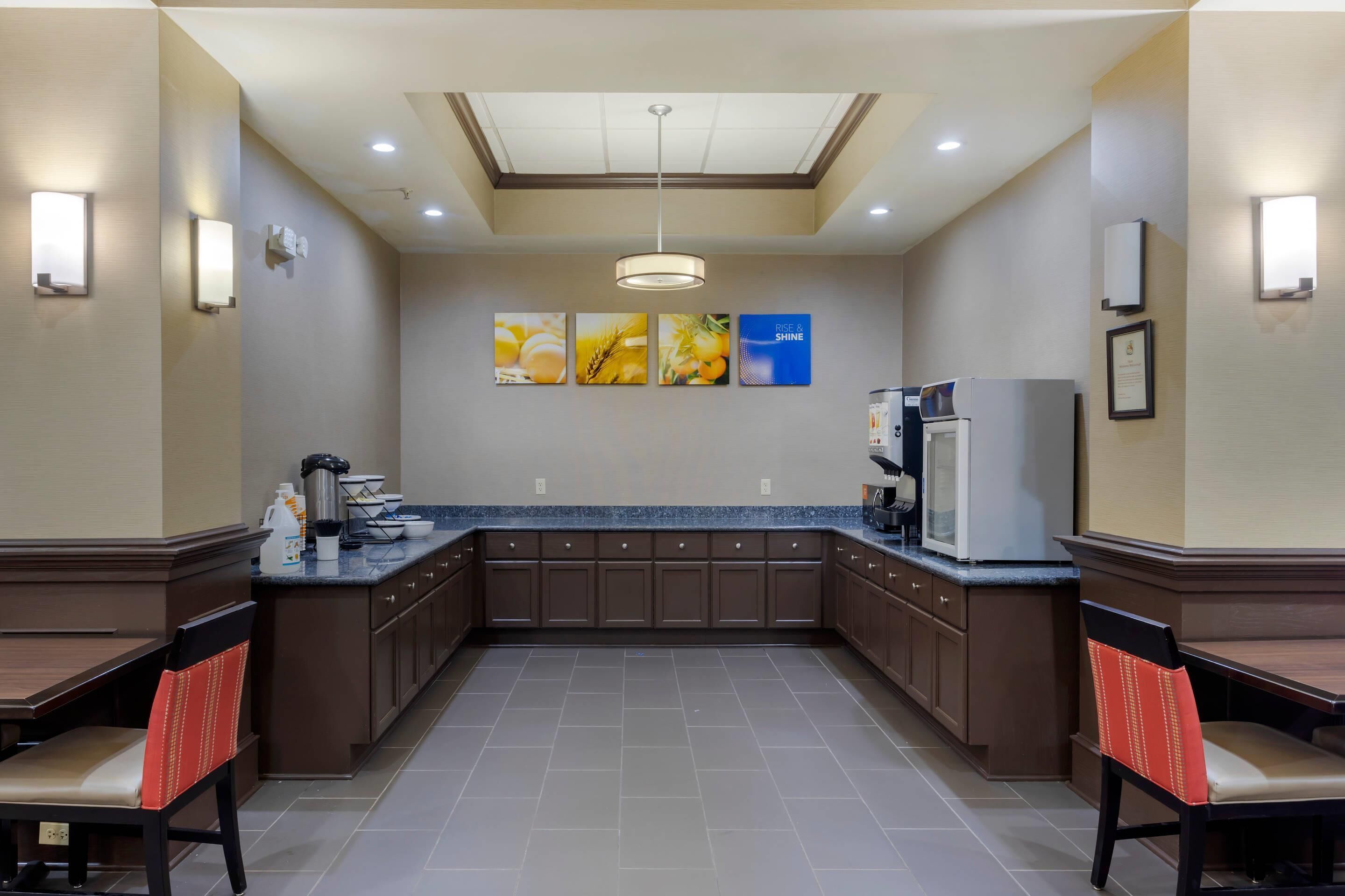 A hotel kitchen with a central island, wall-mounted light fixtures, and a ceiling light.