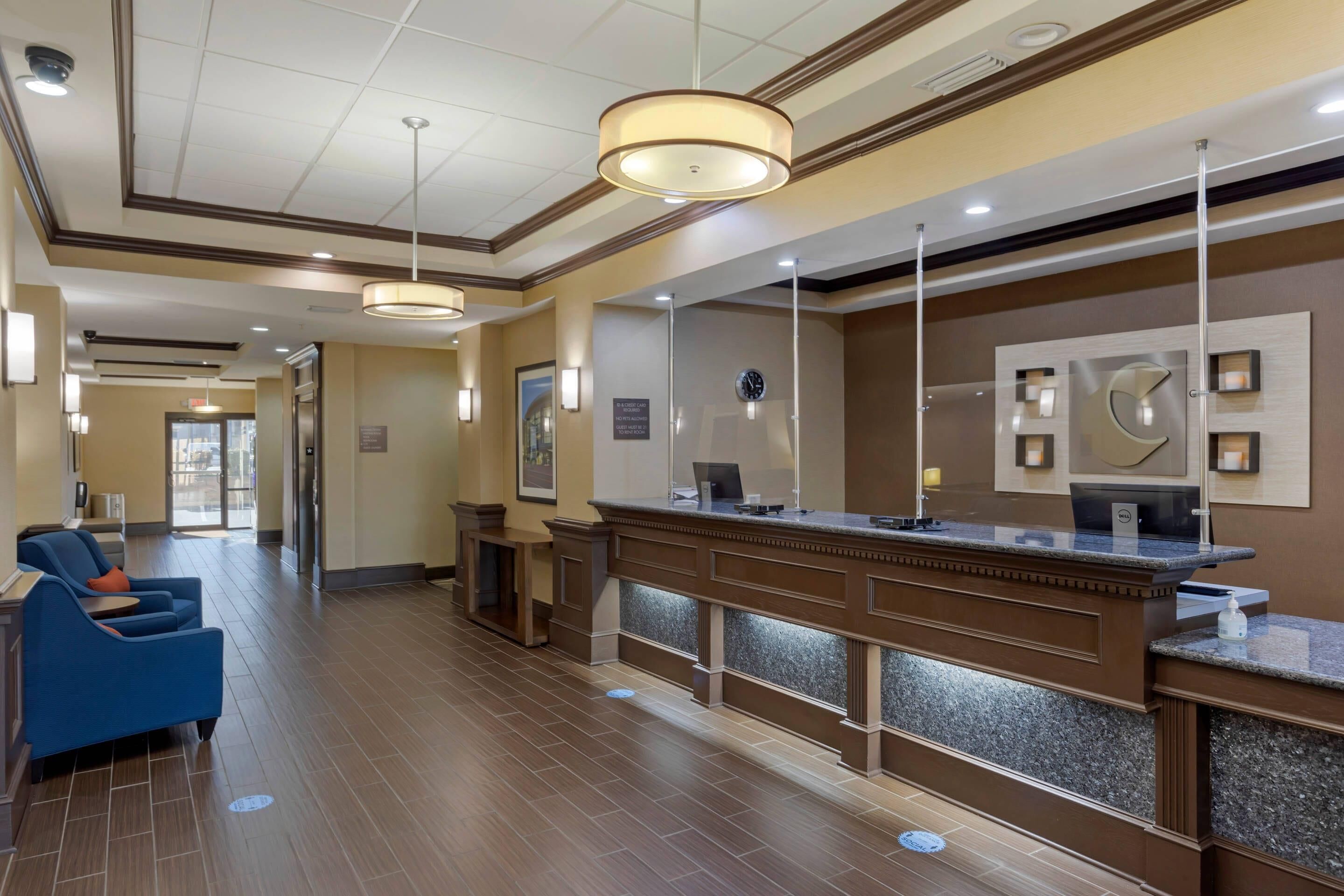 A hotel lobby with a reception desk, seating area, and a clock on the wall.