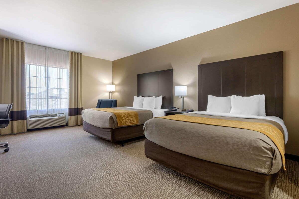 Een hotelkamer met twee bedden, een bureau en een stoel.