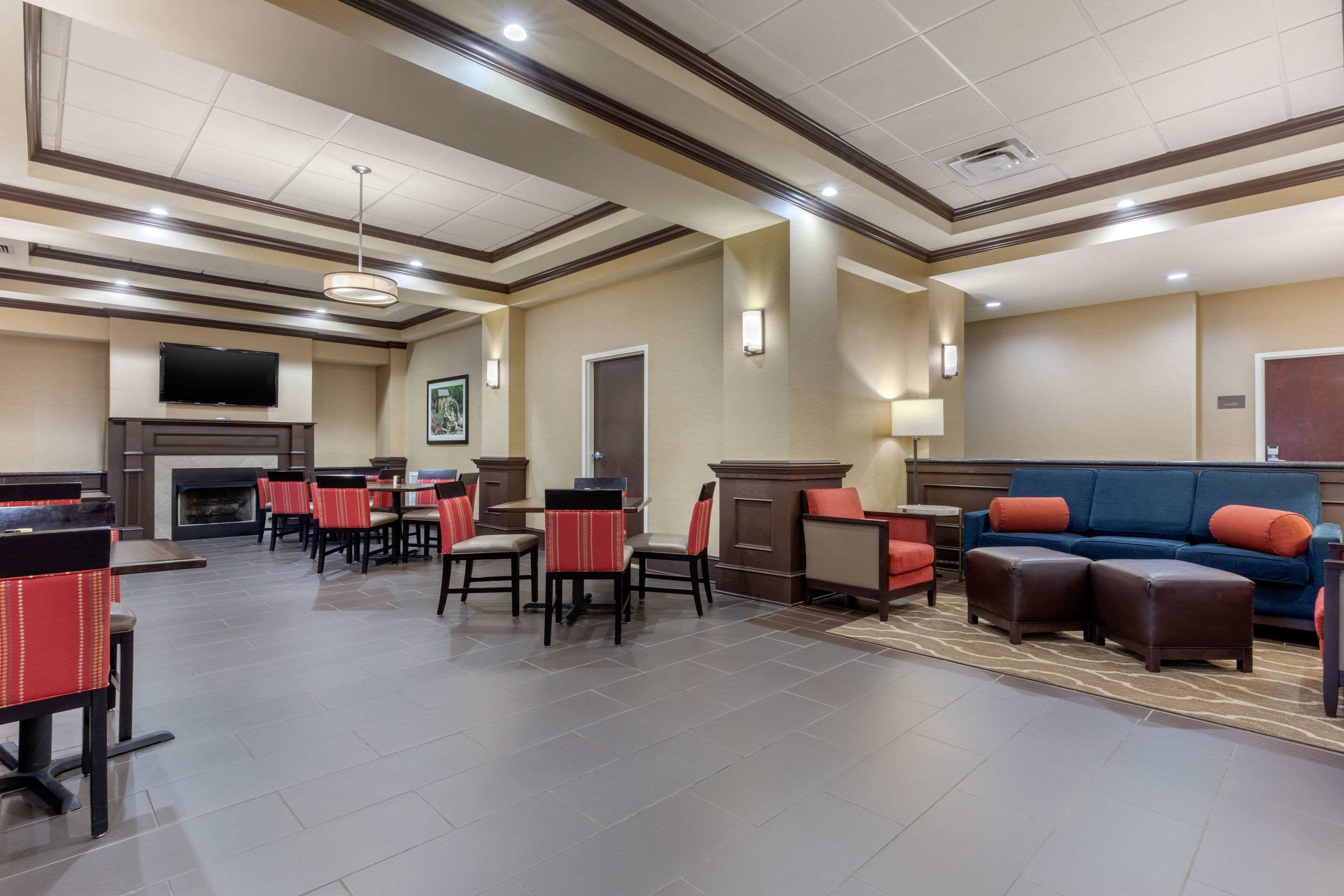 A hotel lobby with a fireplace, seating area, and a television mounted on the wall.