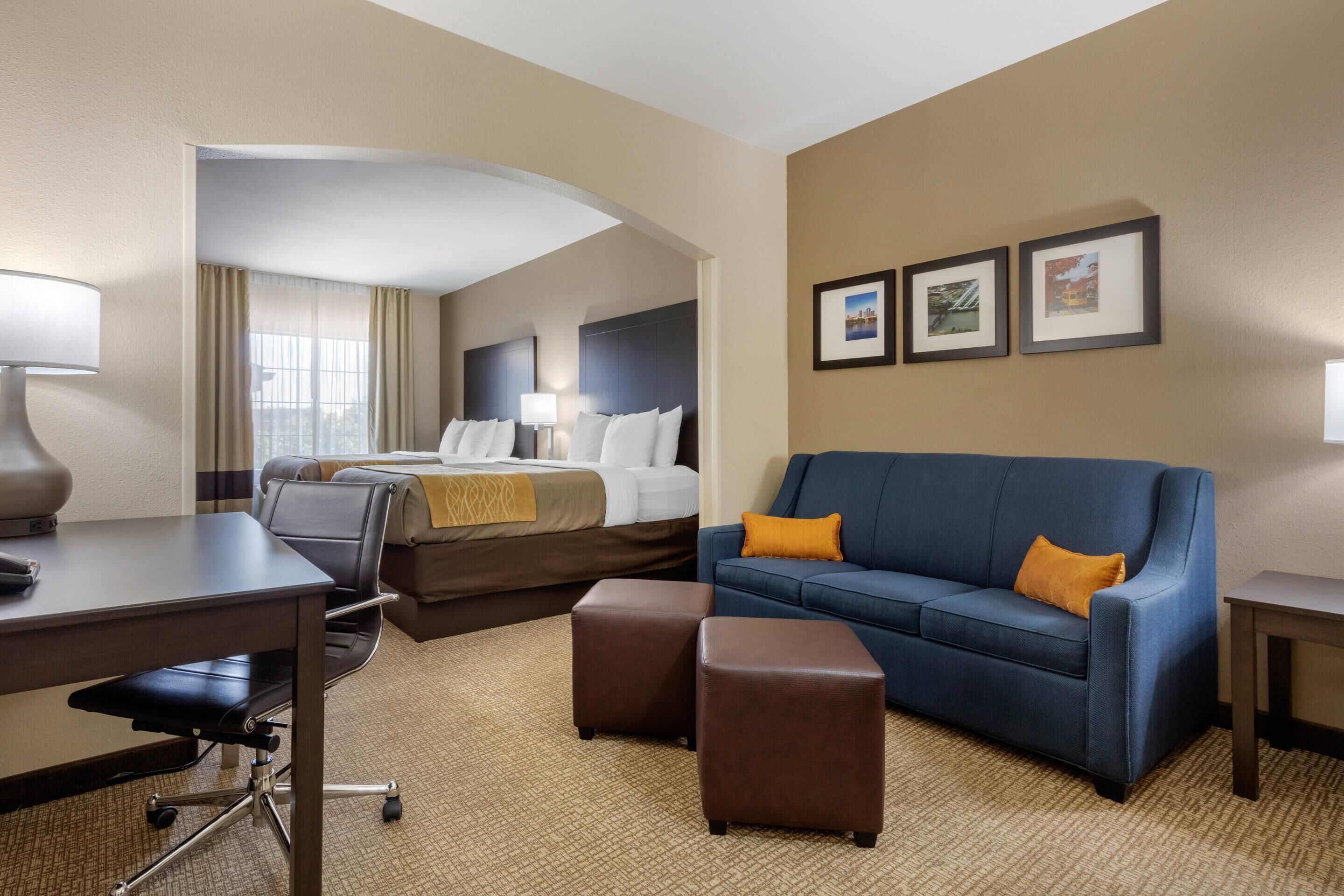 Une chambre d’hôtel avec un lit, un bureau, un canapé bleu et une petite table.