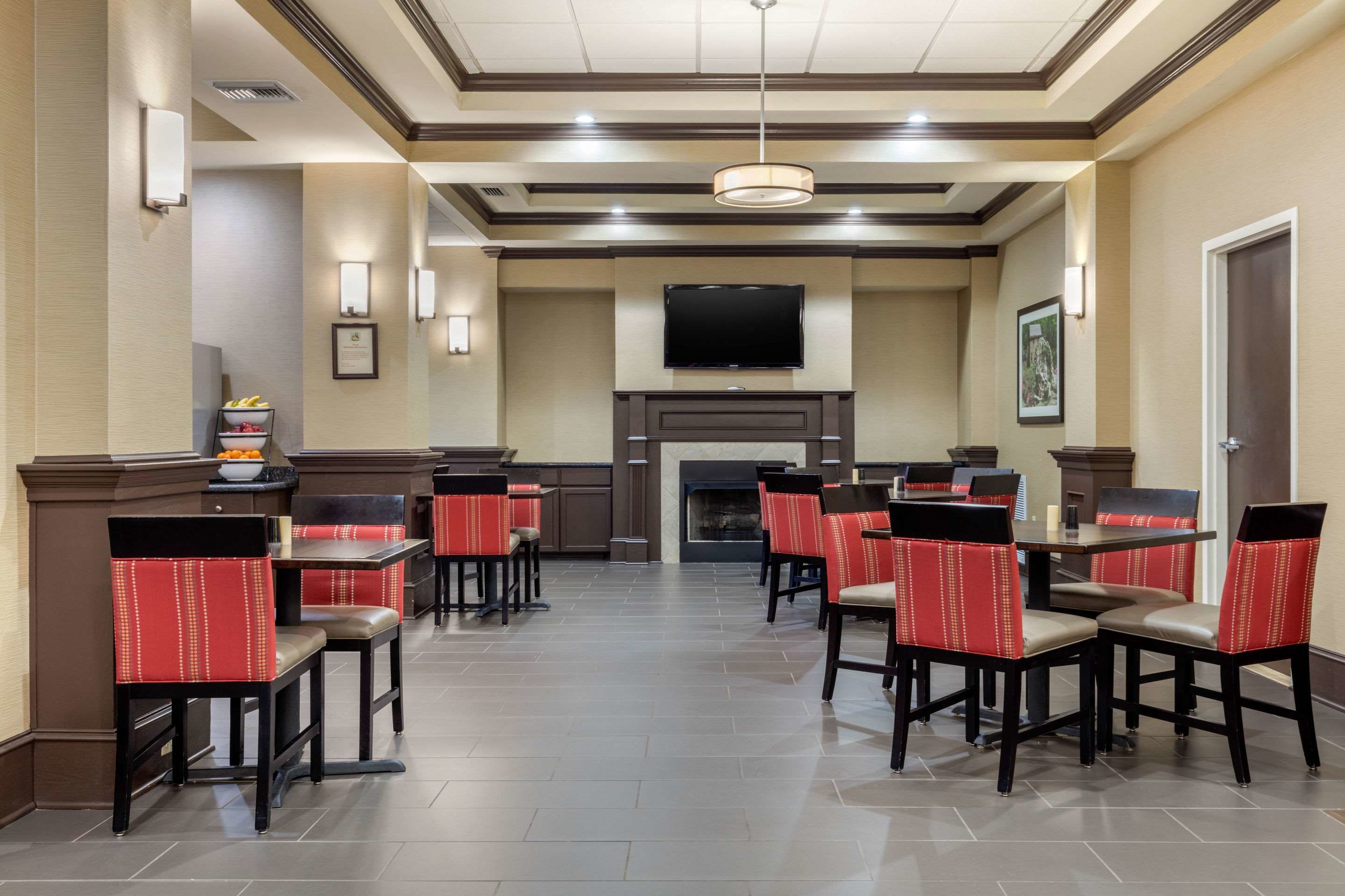 A restaurant with multiple tables and chairs, a flat-screen TV mounted on the wall, and a fireplace.