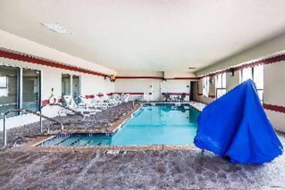 A swimming pool with a blue cover, a lounge area with chairs, and a view of the pool.