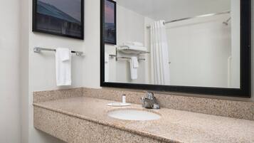 Un baño con encimera de granito, un lavabo, un espejo y una cortina de ducha.