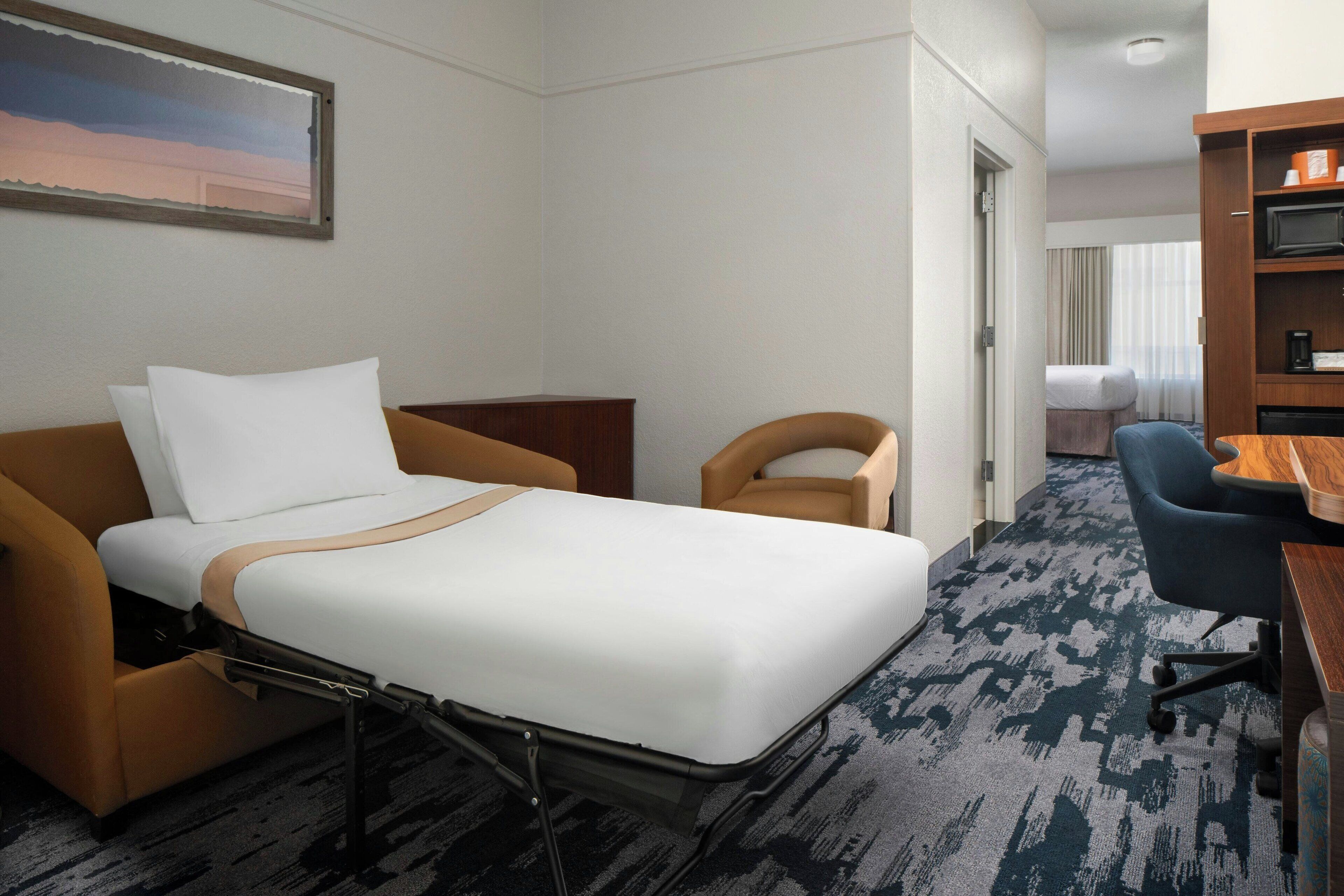 Una habitación de hotel con una cama, un escritorio, una silla y un pequeño armario.