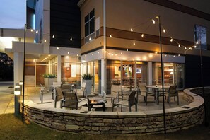 Patio esterno con muri in pietra, arredi da giardino e luci decorative.