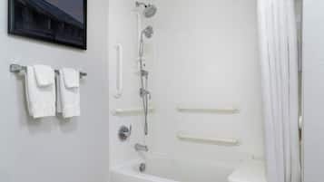 A white bathroom with a bathtub, a shower, and a toilet. There are grab bars installed for safety.