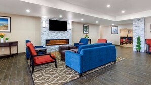 A modern lobby with a stone fireplace, blue sofas, and a flat-screen TV mounted on the wall. - Comfort Suites Copperas Cove (Copperas Cove)