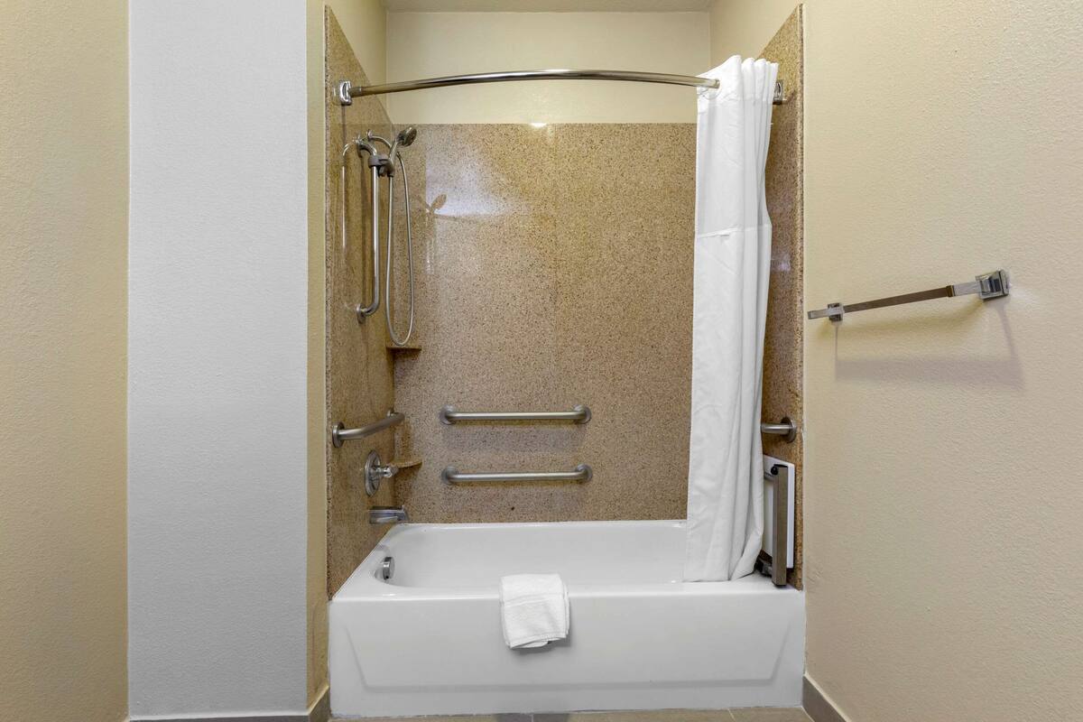 Ein Badezimmer mit Dusche, Haltegriffen und Handtuchhalter.