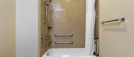Une salle de bain équipée d’une douche, de barres d’appui et d’un porte-serviettes.