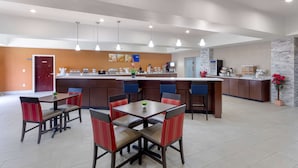 A modern hotel dining area with a central bar, multiple seating options, and a kitchen in the background. - Comfort Suites Copperas Cove (Copperas Cove)