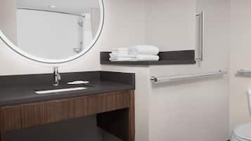 A modern bathroom with a dark wooden vanity, a round mirror, a towel rack, and a toilet.