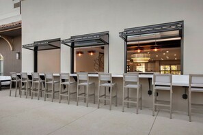 A row of light-colored chairs and tables in a spacious indoor area with large windows and a chandelier. - Courtyard Marriott Paso Robles (Paso Robles)