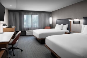 Quarto de hotel com duas camas, uma escrivaninha e uma cadeira.