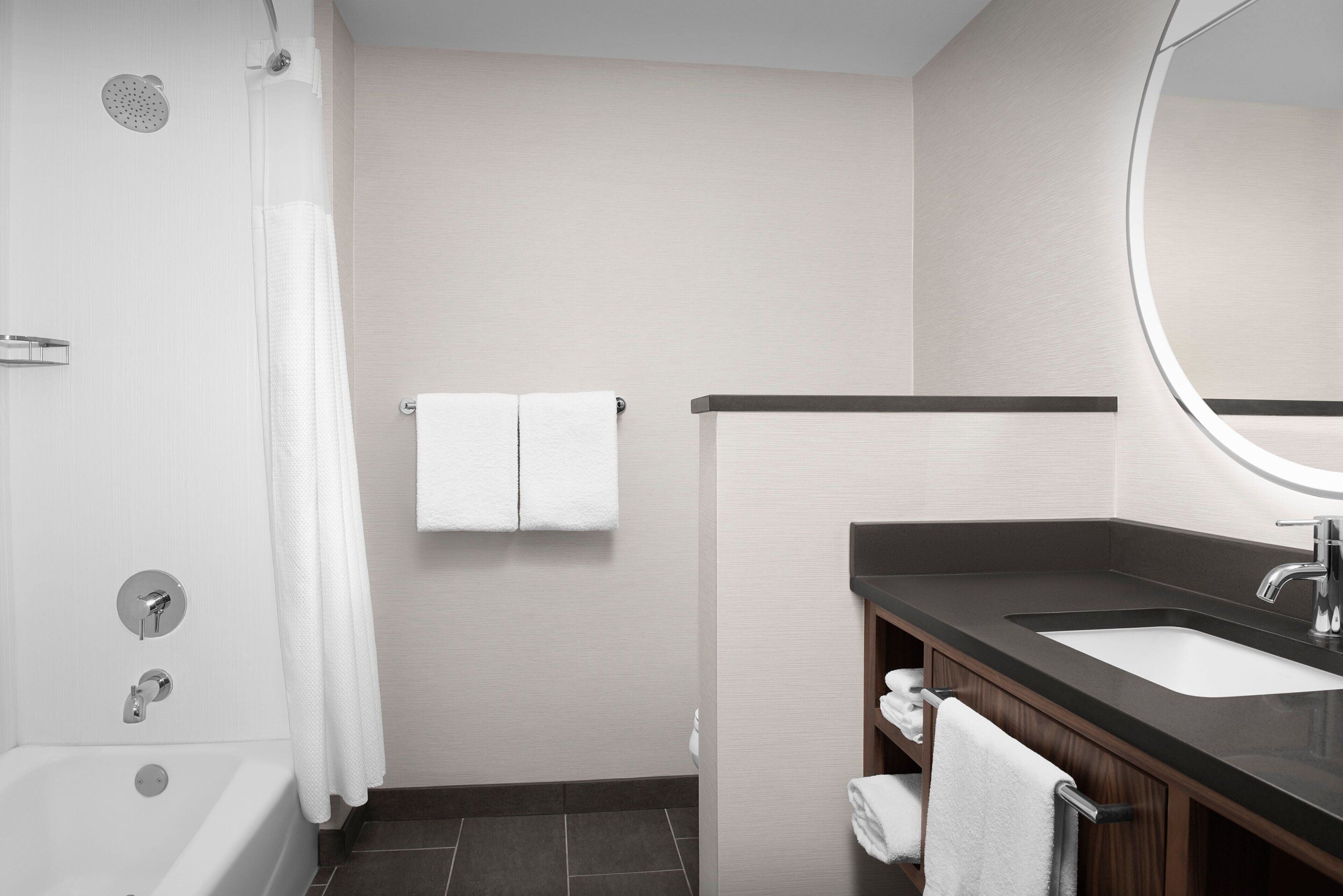 A modern bathroom with a bathtub, a sink, and a mirror.