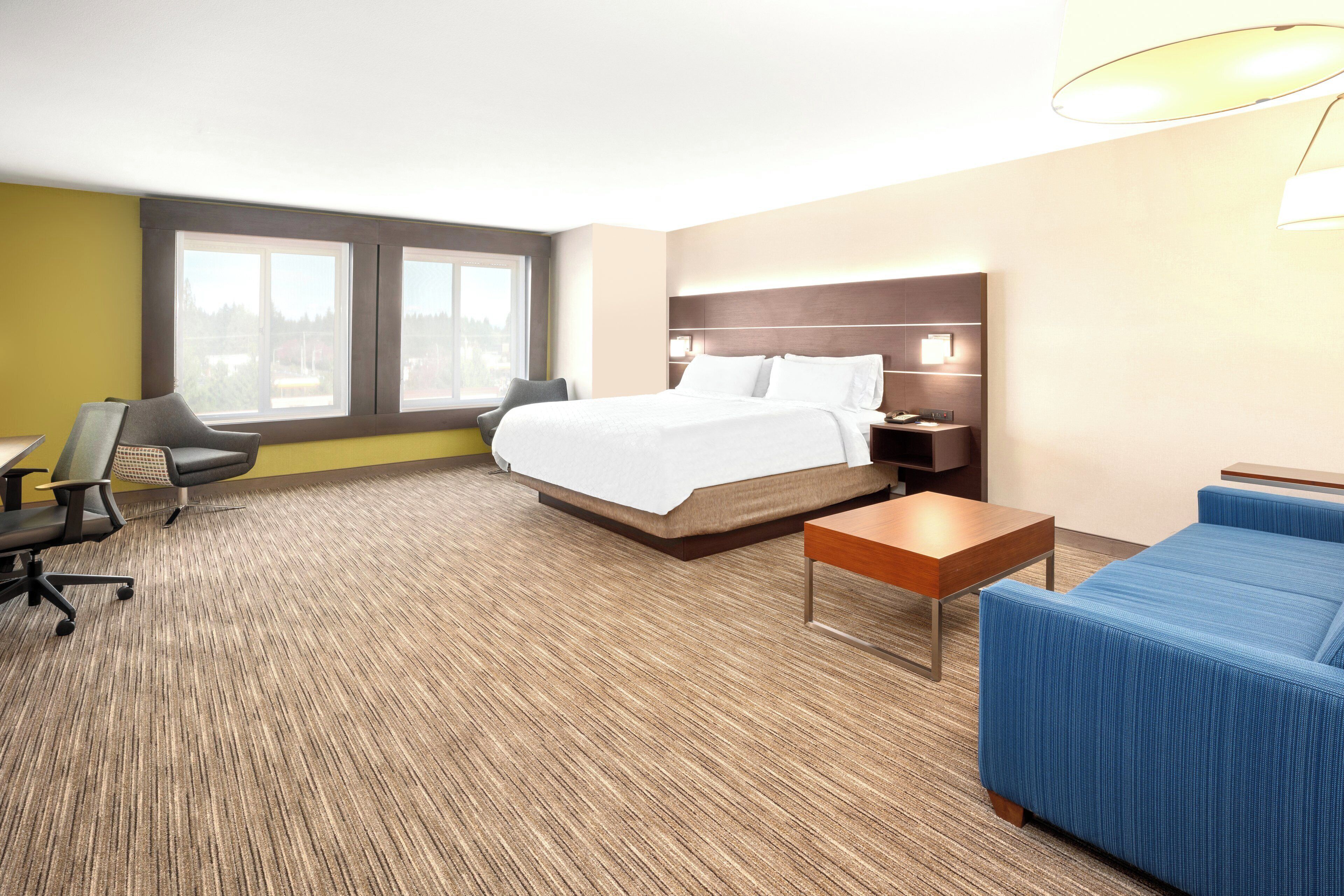 A hotel room with a bed, a desk, a chair, a sofa, and a nightstand.