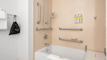 Une salle de bain équipée d’une baignoire, de barres d’appui, d’un porte-serviettes et d’un distributeur de savon.