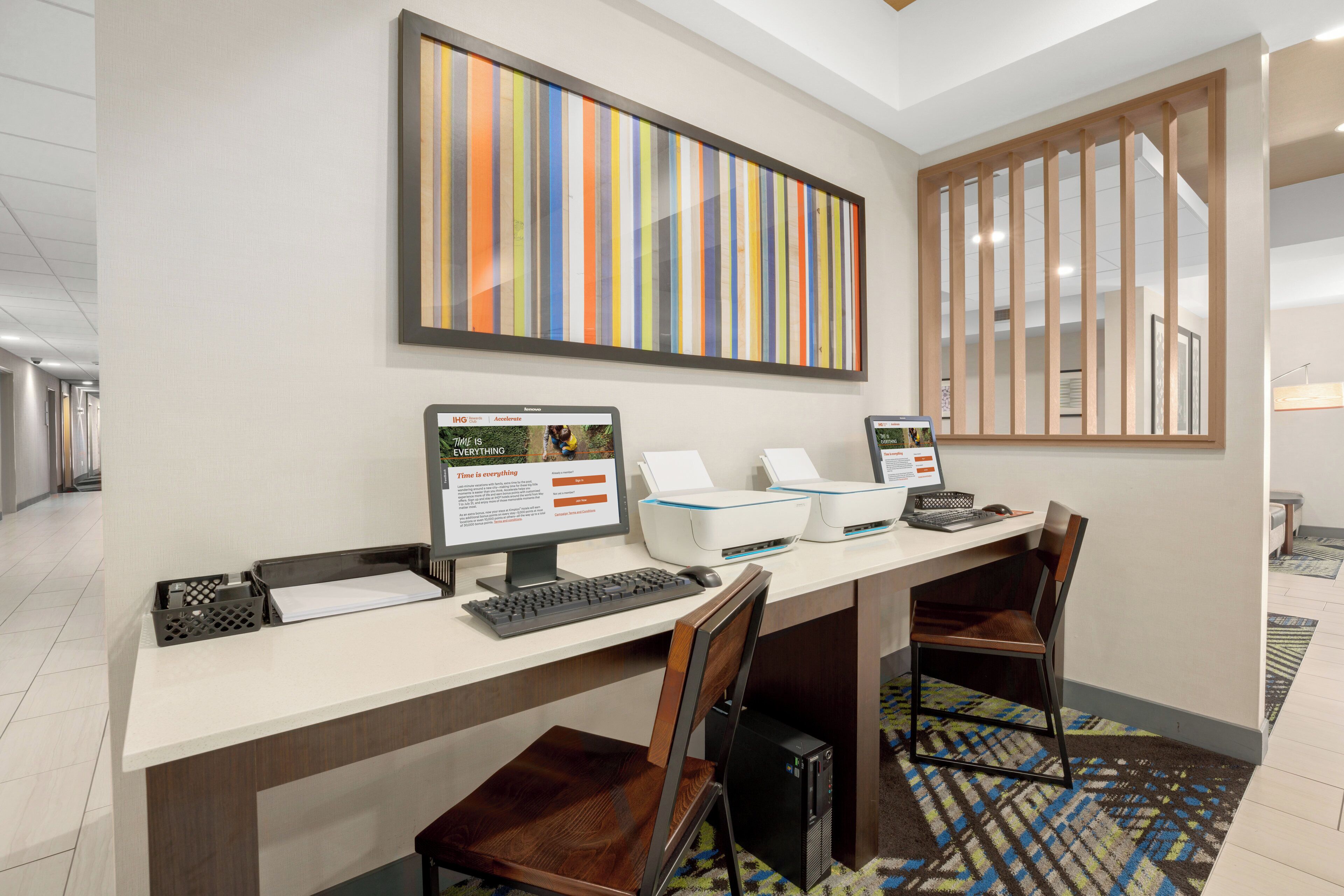 A hotel reception desk with two monitors, a printer, and a computer.