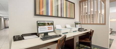 A hotel reception desk with two monitors, a printer, and a computer.