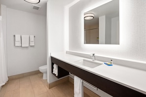 A modern bathroom with a white sink, dark vanity, and a large mirror.