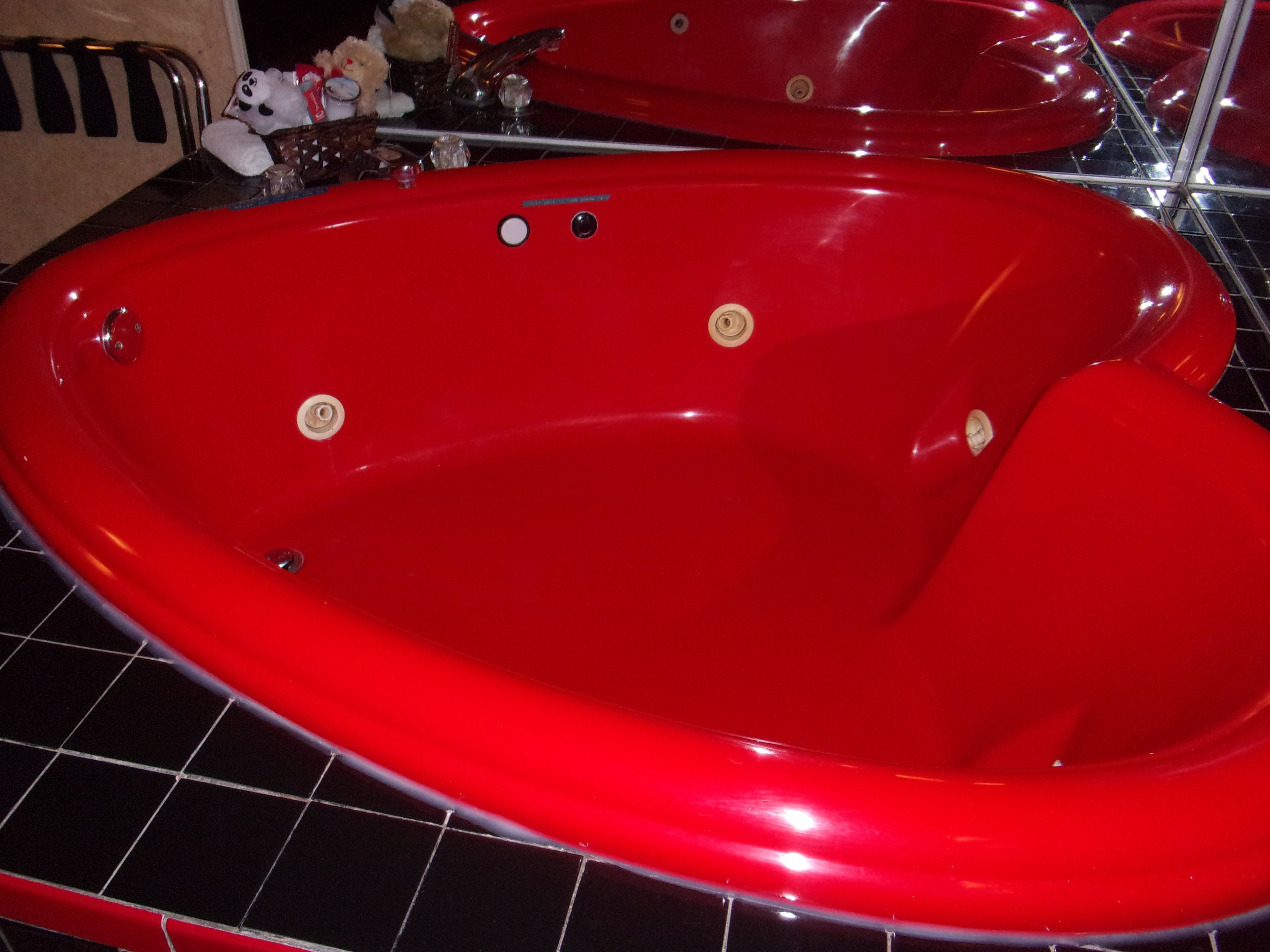 A red bathtub with a chrome faucet and two control knobs.