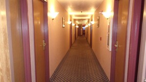 Ein Hotelkorridor mit Holztüren, Zimmernummern und einem gemusterten Teppich.