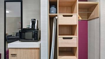 A kitchenette with a microwave, a coffee maker, and wooden storage cabinets.