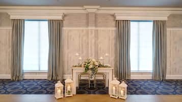 A room with a wooden floor, a table with a floral centerpiece, and two chairs.