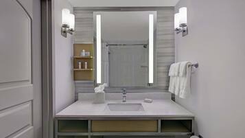Un baño moderno con un espejo grande, un lavabo y una zona de ducha.