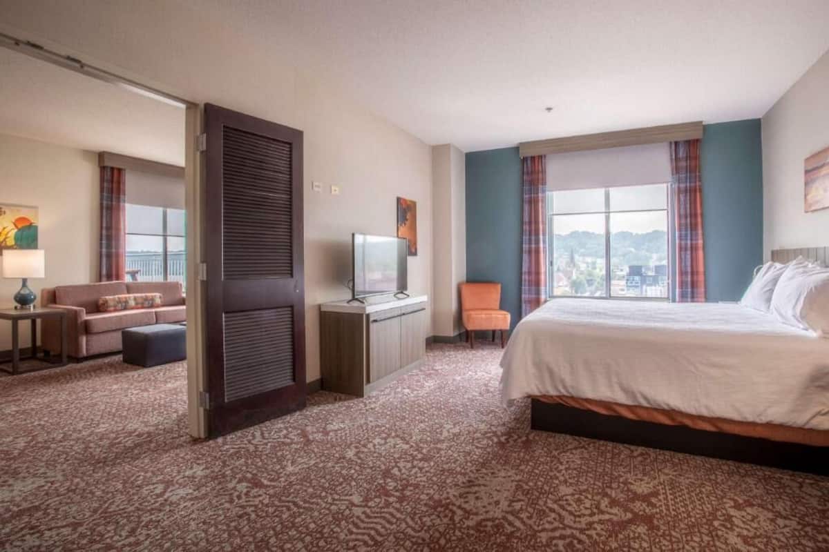 Una habitación de hotel con una cama, un escritorio con televisor, un sofá y una silla.