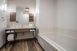 A modern bathroom with a wooden vanity, white sink, and a large bathtub. - Hilton Garden Inn Mankato Downtown (Mankato)