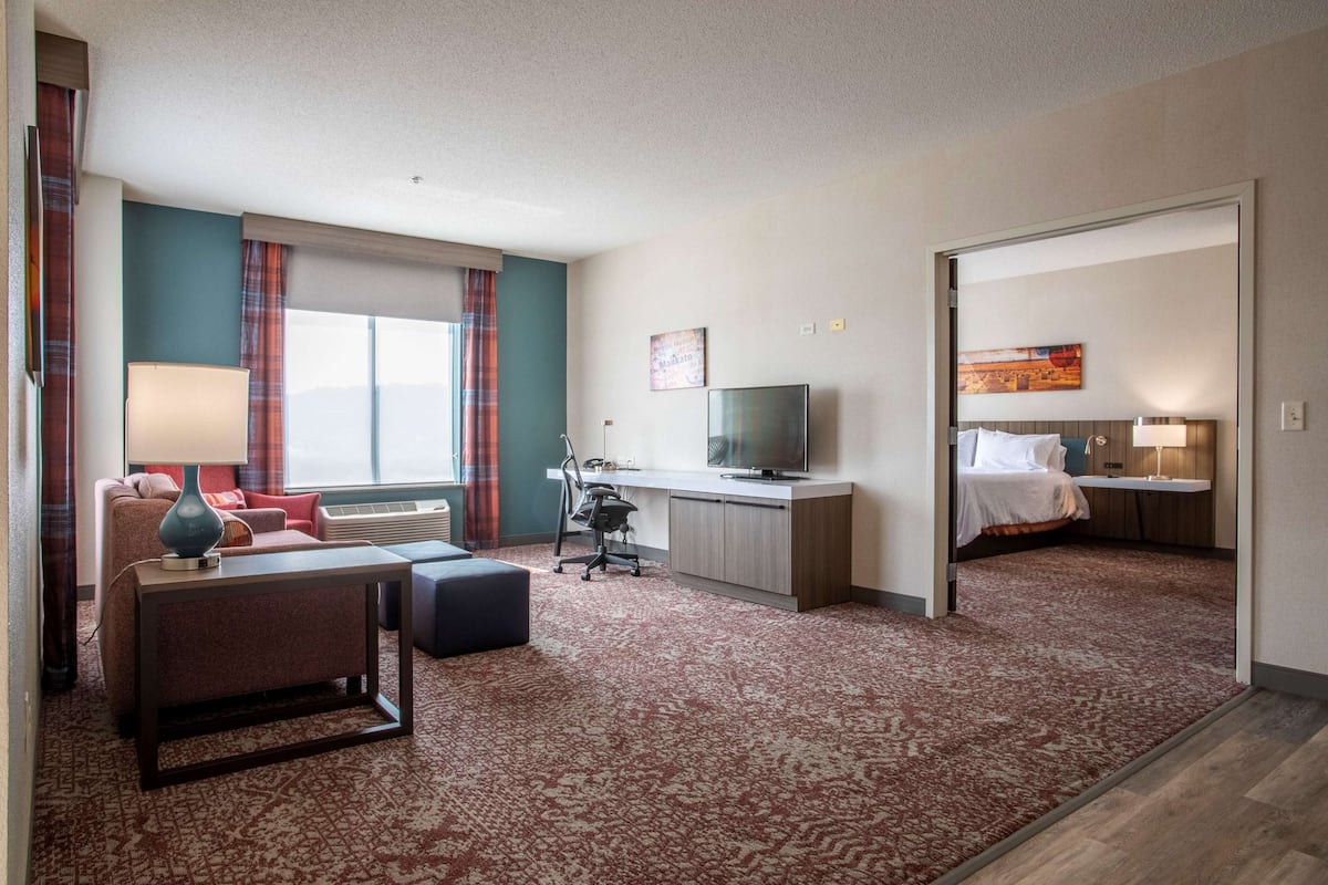 Habitación de hotel con sofá, escritorio, televisión, cama y piso alfombrado.