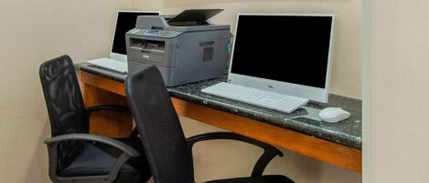 Un espacio de trabajo con dos computadoras, una impresora y dos sillas de oficina.