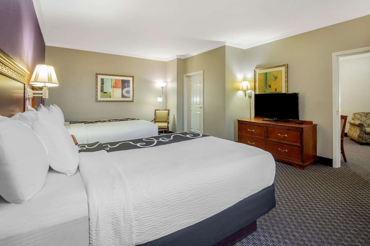 A hotel room with a large bed, a television, a dresser, and a door.