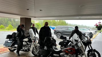 Un espace de stationnement couvert où sont garées des motos et des voitures.