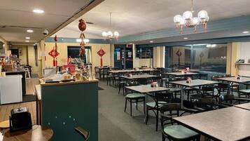 A restaurant with multiple tables and chairs, a counter area, and decorative elements on the walls.